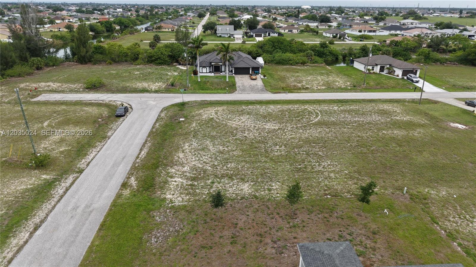 An aerial view shows a vacant residential lot situated across from a single-family home — 2009 NW 2ND AVE, Cape Coral FL 33993, CAPE CORAL, FL