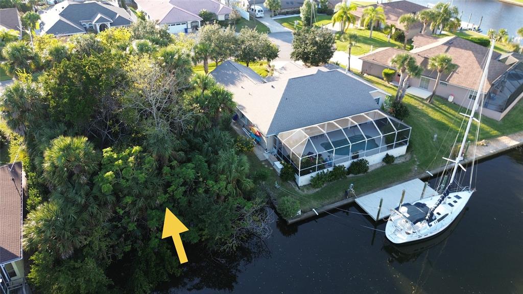 An aerial view shows a waterfront house with a pool cage and a docked sailboat — 4 CROW COURT, PALM COAST, FL