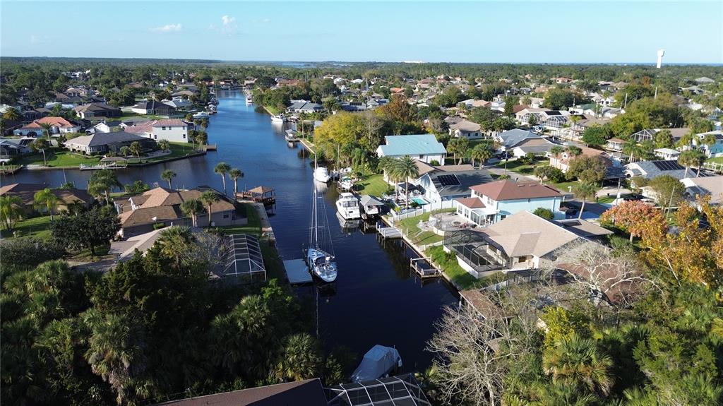 An aerial view shows houses along a canal with several boats docked at private piers — 4 CROW COURT, PALM COAST, FL
