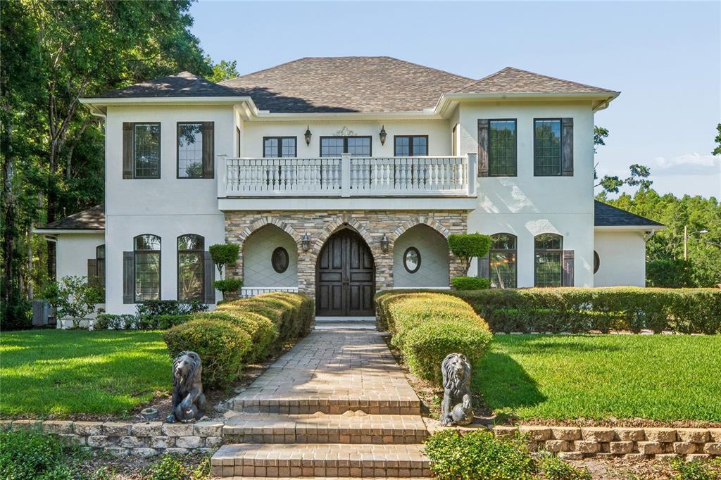 A two-story stucco house with a stone entryway, a balcony, and a brick walkway — 3530 OLD KEYSTONE ROAD, TARPON SPRINGS, FL