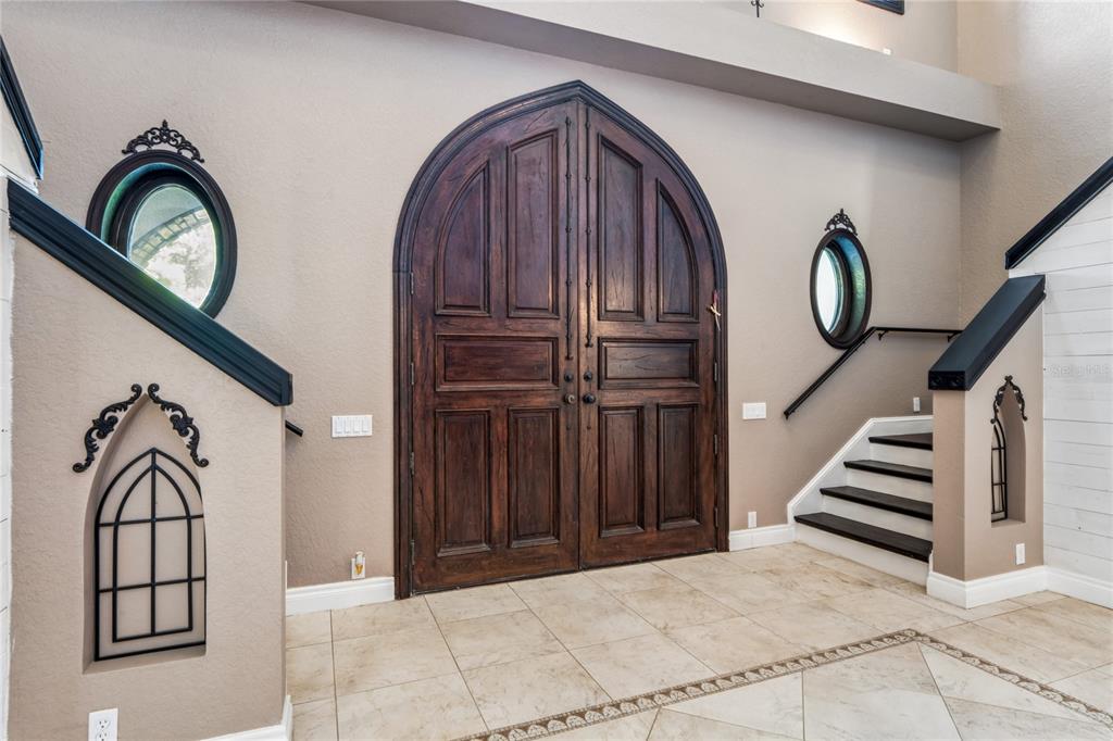 An entryway features a large arched wooden double door, tiled floors, and two staircases — 3530 OLD KEYSTONE ROAD, TARPON SPRINGS, FL