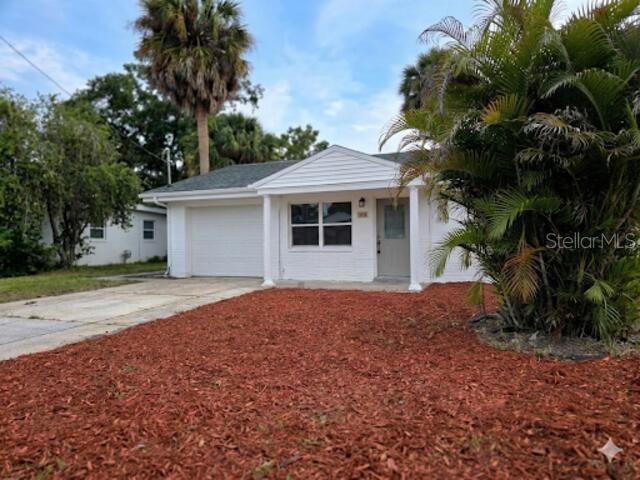 A white, single-story house with a garage and red mulch landscaping under a blue sky — 6703 SANDRA DRIVE, PORT RICHEY, FL