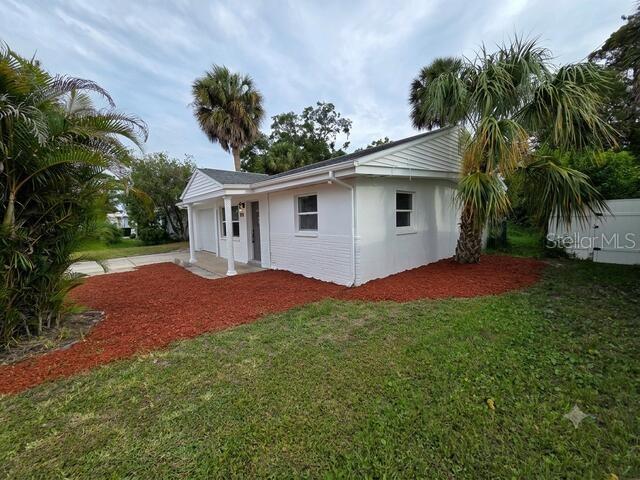 A white single-story house with a red mulch yard and palm trees — 6703 SANDRA DRIVE, PORT RICHEY, FL