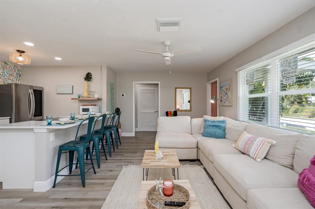 An open-concept living room and kitchen featuring a white sectional sofa and breakfast bar seating — 617 26TH STREET W, BRADENTON, FL