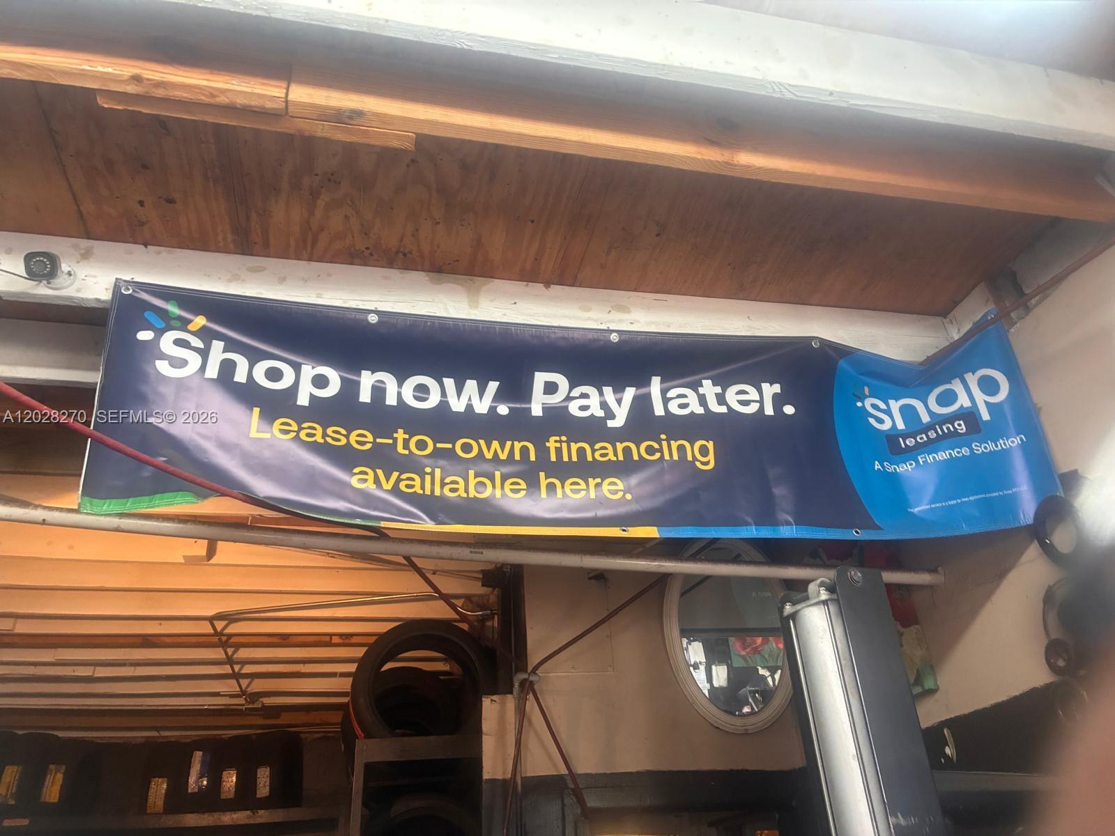A banner advertising lease-to-own financing hangs from the wooden ceiling of a garage — 2337 N 21st Ave, Hollywood FL 33020, HOLLYWOOD, FL