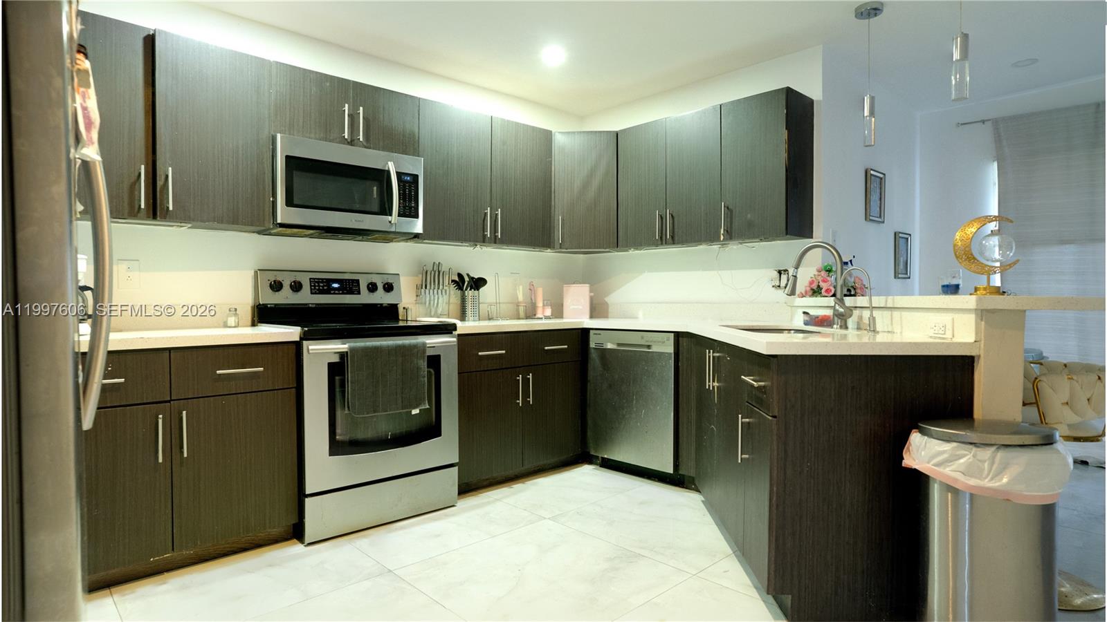 A kitchen features dark wood cabinets, stainless steel appliances, and white countertops — 18499 NW 52nd Path, Miami Gardens FL 33055, MIAMI GARDENS, FL