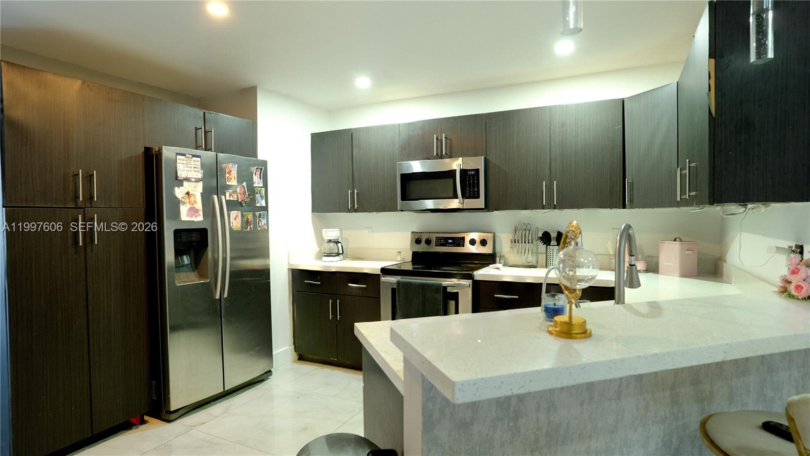 A kitchen features dark wood cabinets, stainless steel appliances, and white quartz countertops — 18499 NW 52nd Path, Miami Gardens FL 33055, MIAMI GARDENS, FL