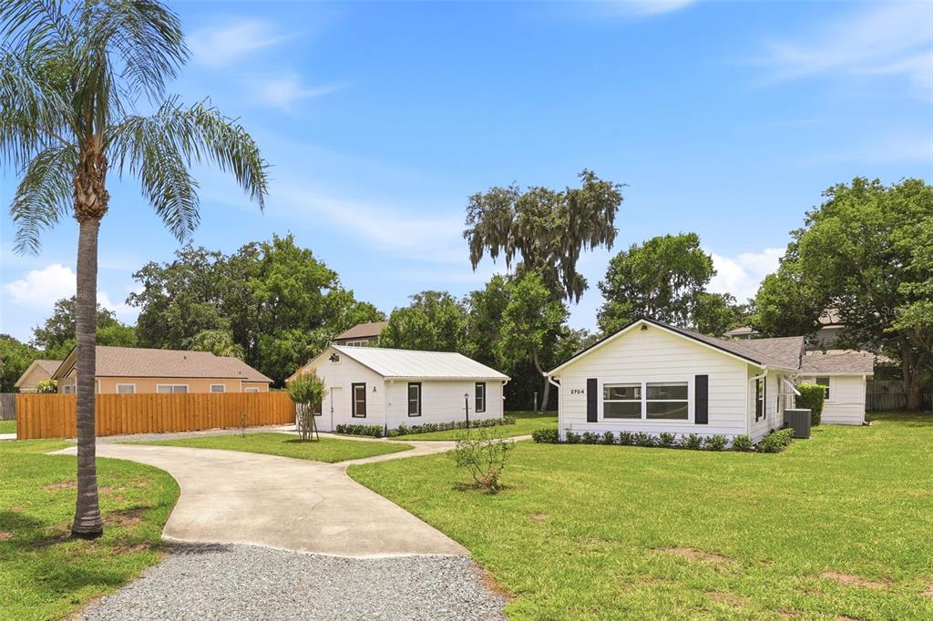 A gravel driveway leads to two white houses on a grassy lot with a palm tree — 2704 E JEFFERSON STREET, ORLANDO, FL