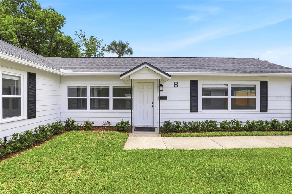 The exterior of a white single-story house with black shutters and a front door labeled B — 2704 E JEFFERSON STREET, ORLANDO, FL