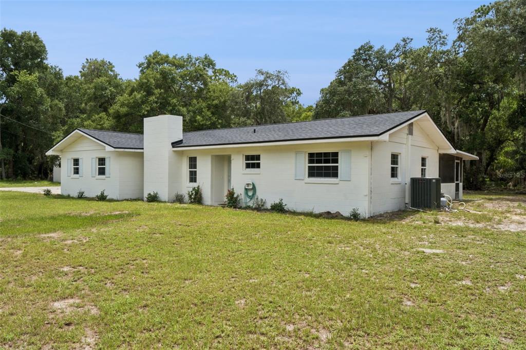 A white, single-story ranch-style house with a dark roof sits on a grassy lot — 2650 HARRY AVENUE, ORANGE CITY, FL
