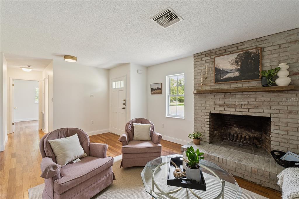 A living room features a brick fireplace, two pink armchairs, and hardwood flooring — 2650 HARRY AVENUE, ORANGE CITY, FL