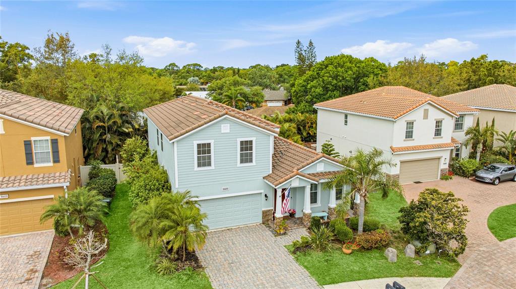 An aerial view shows a light blue two-story house with a paved driveway and landscaping — 5603 AARON COURT, SARASOTA, FL