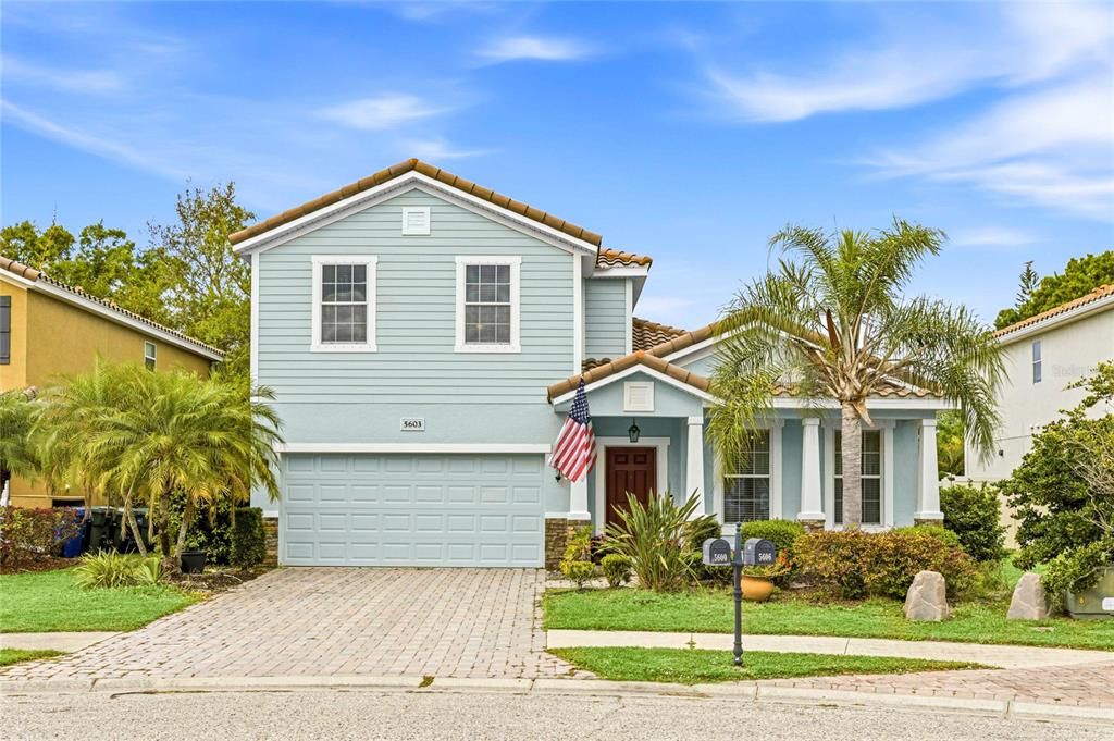 A two-story, light blue house with a paved driveway, a garage, and a palm tree — 5603 AARON COURT, SARASOTA, FL