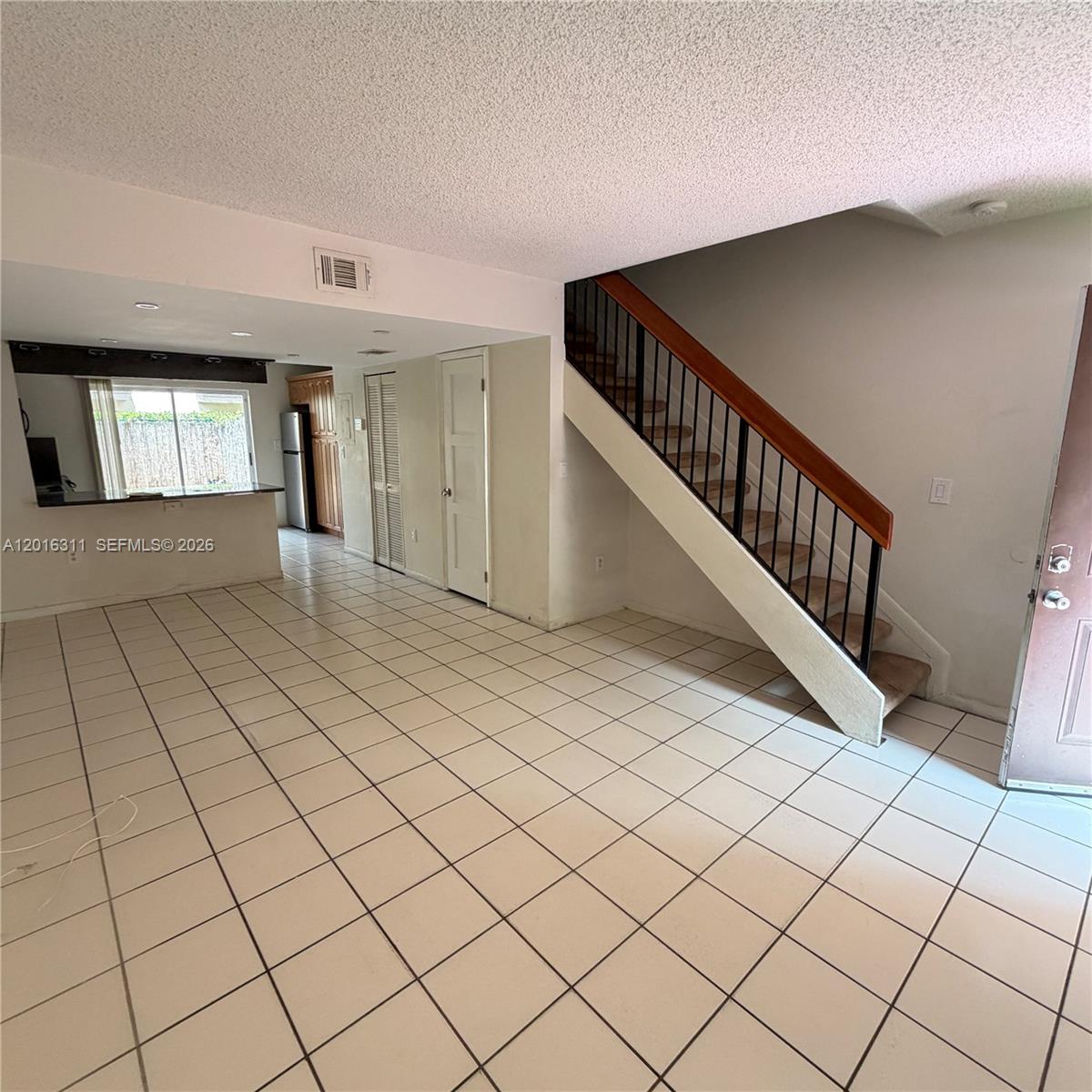 An interior view shows a tiled living area with a staircase and an open kitchen — 680 NW 82nd Pl # 264, Miami FL 33126, MIAMI, FL