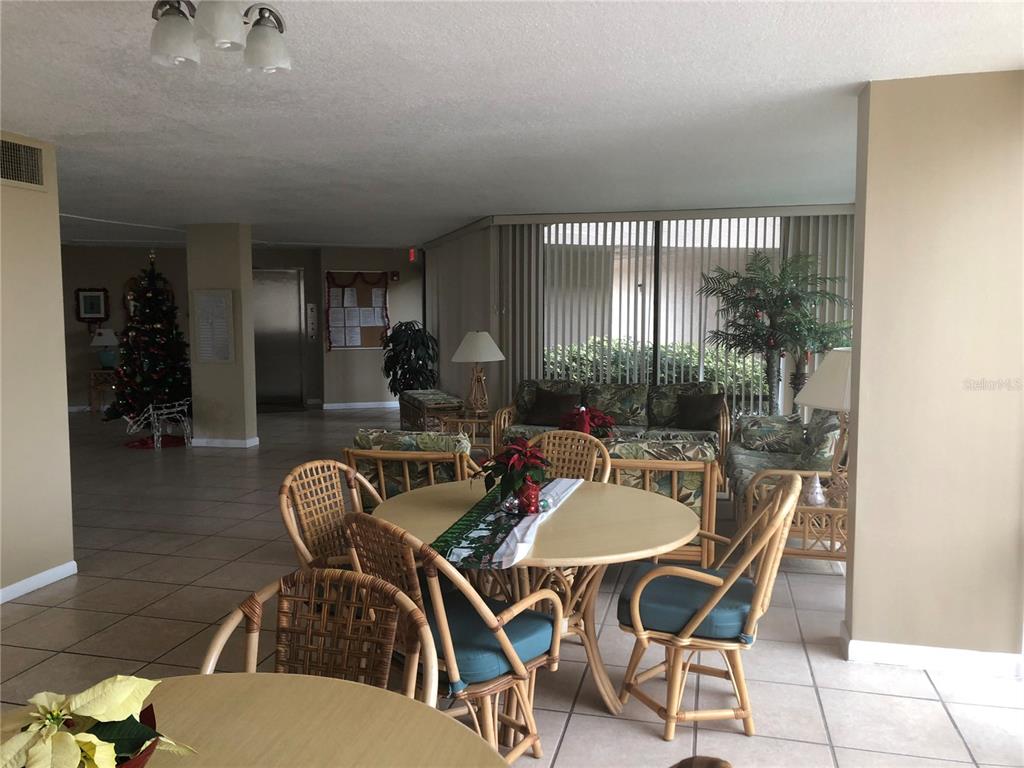 A common area features tile floors, wicker furniture, round tables, and a decorated Christmas tree — 17580 GULF BOULEVARD UNIT 206, REDINGTON SHORES, FL