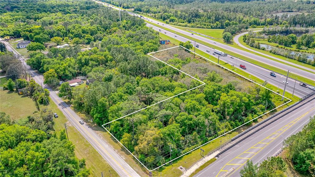 An aerial view shows a wooded, rectangular plot of land bordered by two roads — W MAIN STREET, LAKE HELEN, FL