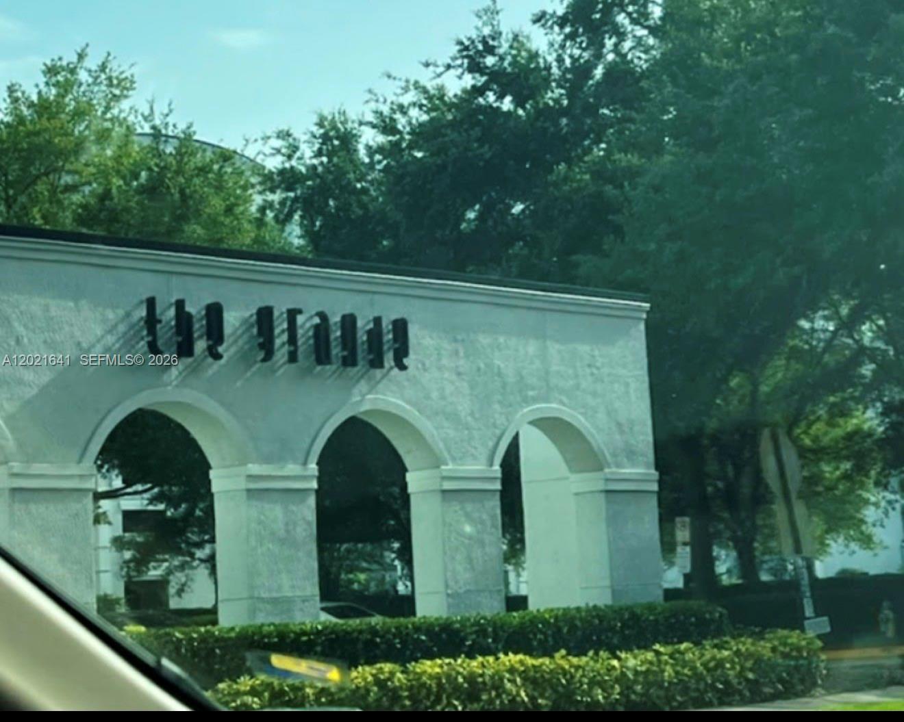 A white stucco building exterior features arched entryways and black lettering reading The Grove — 204 E South street # 1061, Orlando FL 32801, ORLANDO, FL