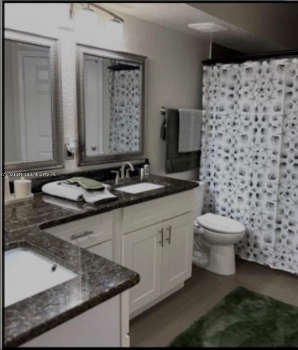A bathroom features a double vanity with dark granite countertops, white cabinets, and a shower curtain — 204 E South street # 1061, Orlando FL 32801, ORLANDO, FL
