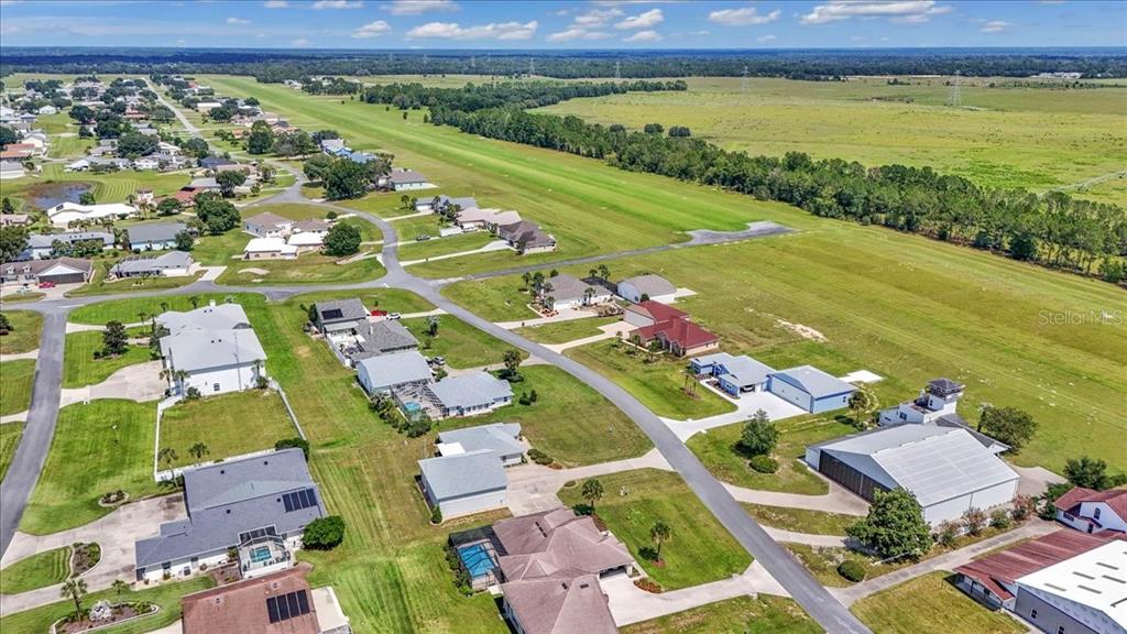 An aerial view shows a residential airpark neighborhood with houses, hangars, and a grass runway — 9700 SE 72ND AVENUE, OCALA, FL
