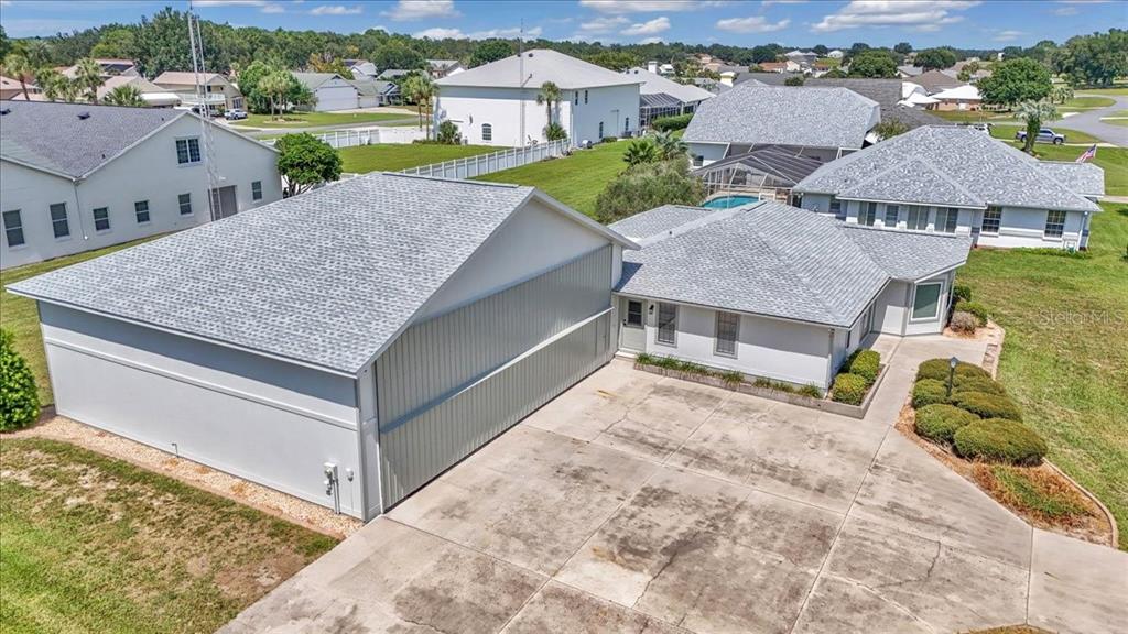 An aerial view shows a house with an attached hangar and a concrete driveway — 9700 SE 72ND AVENUE, OCALA, FL