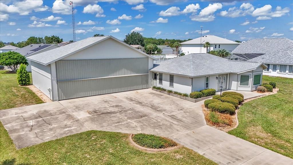An exterior view of a house with an attached airplane hangar and concrete driveway — 9700 SE 72ND AVENUE, OCALA, FL