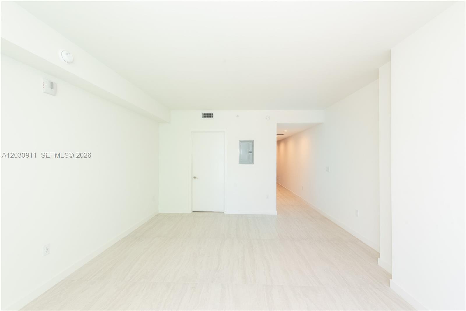 An empty room with white walls, light wood-look flooring, and a closed white door — 77 SE 5th Street # 1804, Miami FL 33131, MIAMI, FL