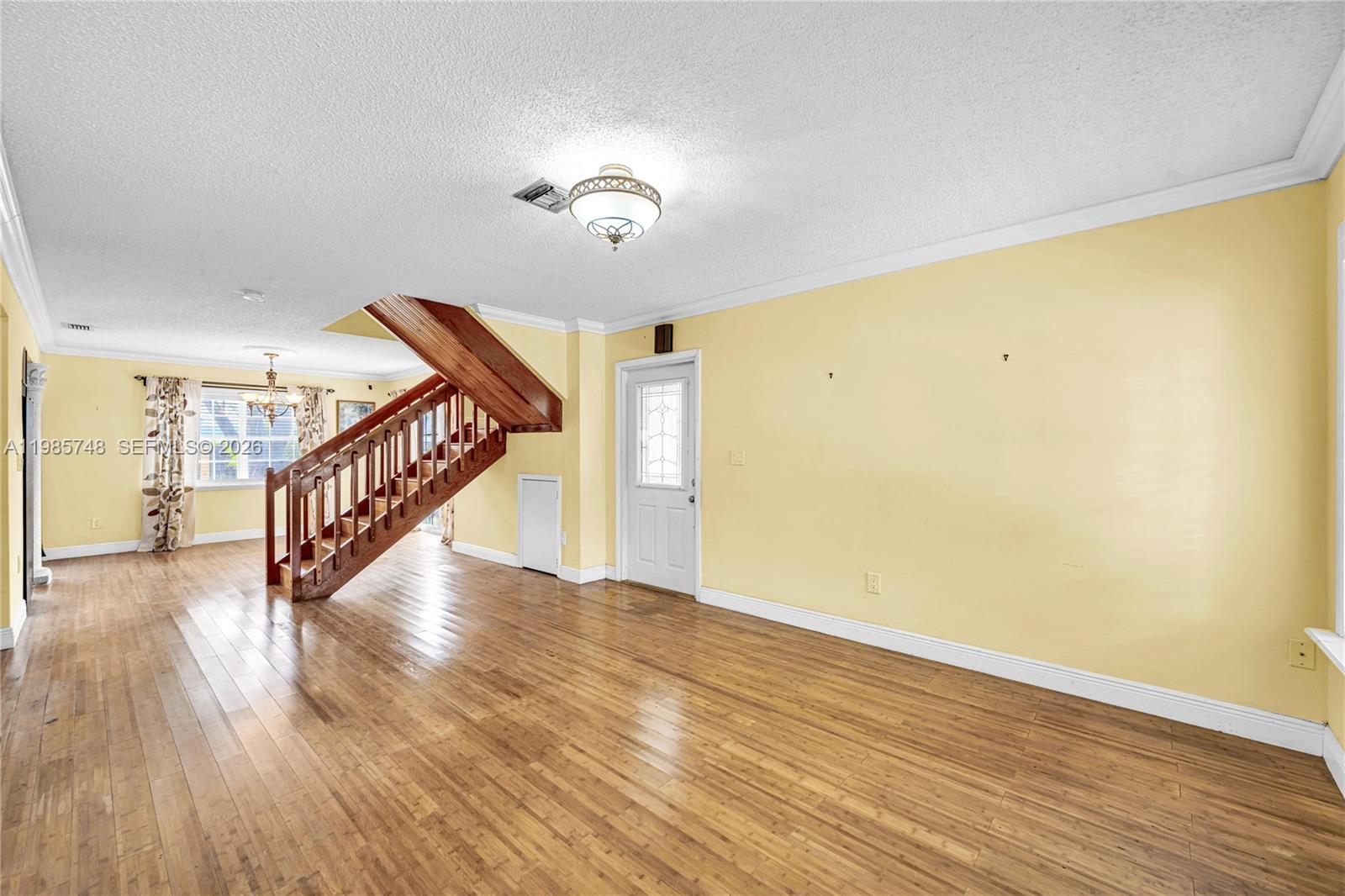A living room features hardwood floors, yellow walls, and a wooden staircase — 11455 SW 117 Ct, Miami FL 33186, MIAMI, FL