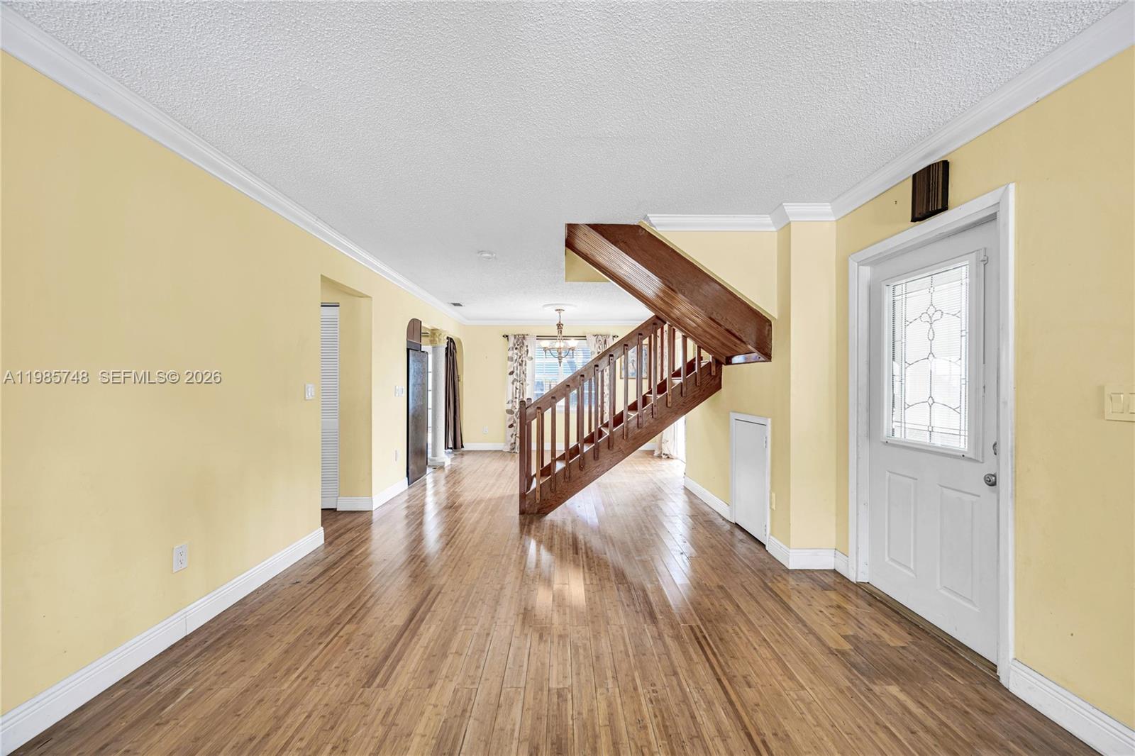 A living room features yellow walls, hardwood floors, and a prominent wooden staircase — 11455 SW 117 Ct, Miami FL 33186, MIAMI, FL
