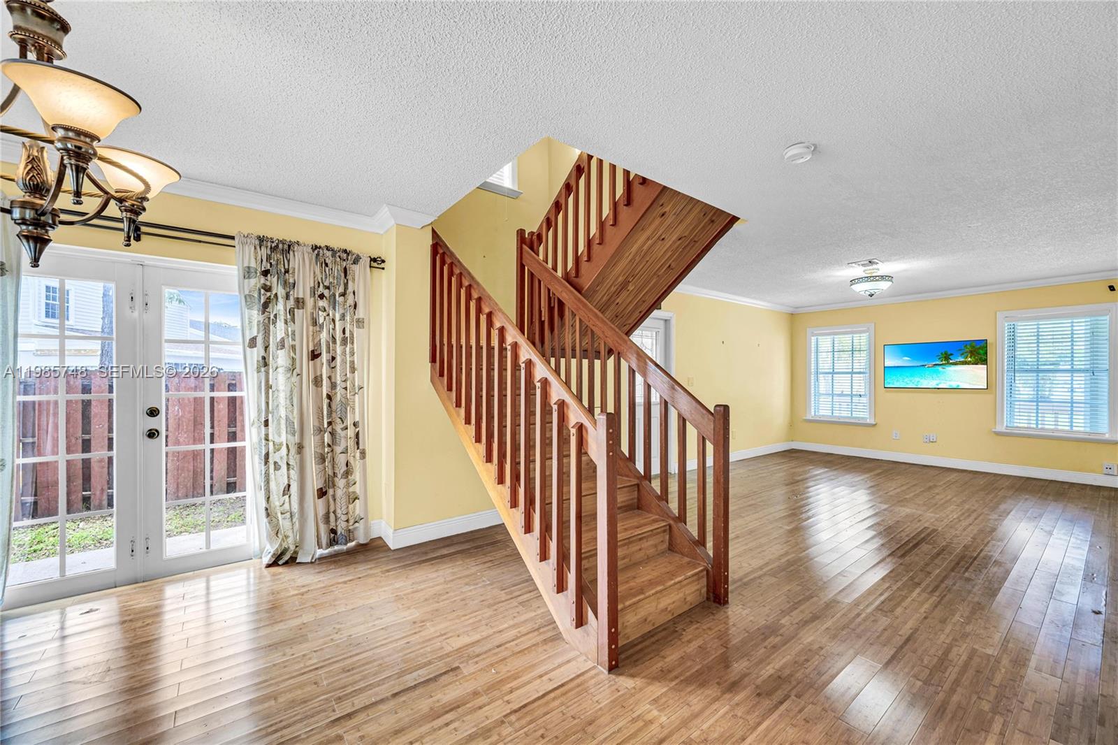 A living room features yellow walls, hardwood floors, and a central wooden staircase — 11455 SW 117 Ct, Miami FL 33186, MIAMI, FL