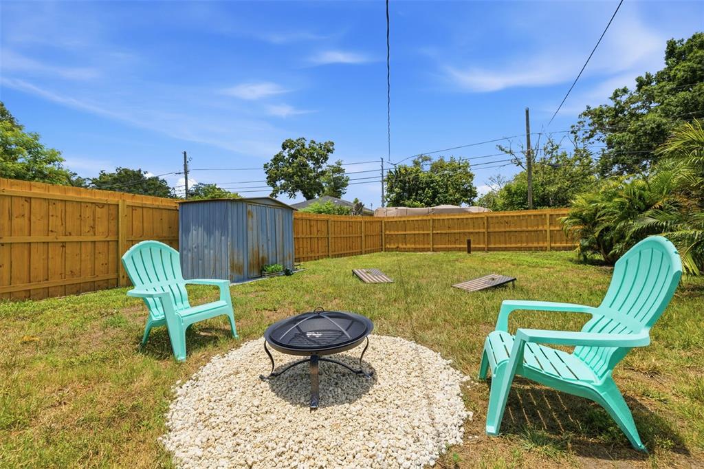 A backyard features a fire pit, two light blue chairs, and a metal storage shed — 2237 14TH AVENUE N, ST PETERSBURG, FL