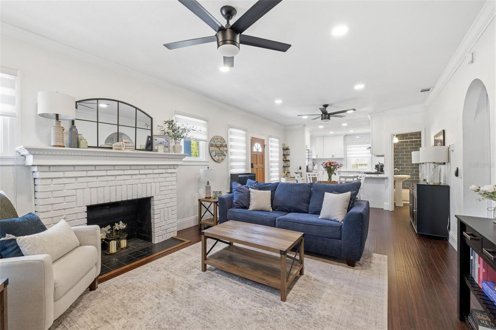A living room features a white brick fireplace, blue sofa, and dark wood flooring — 2237 14TH AVENUE N, ST PETERSBURG, FL