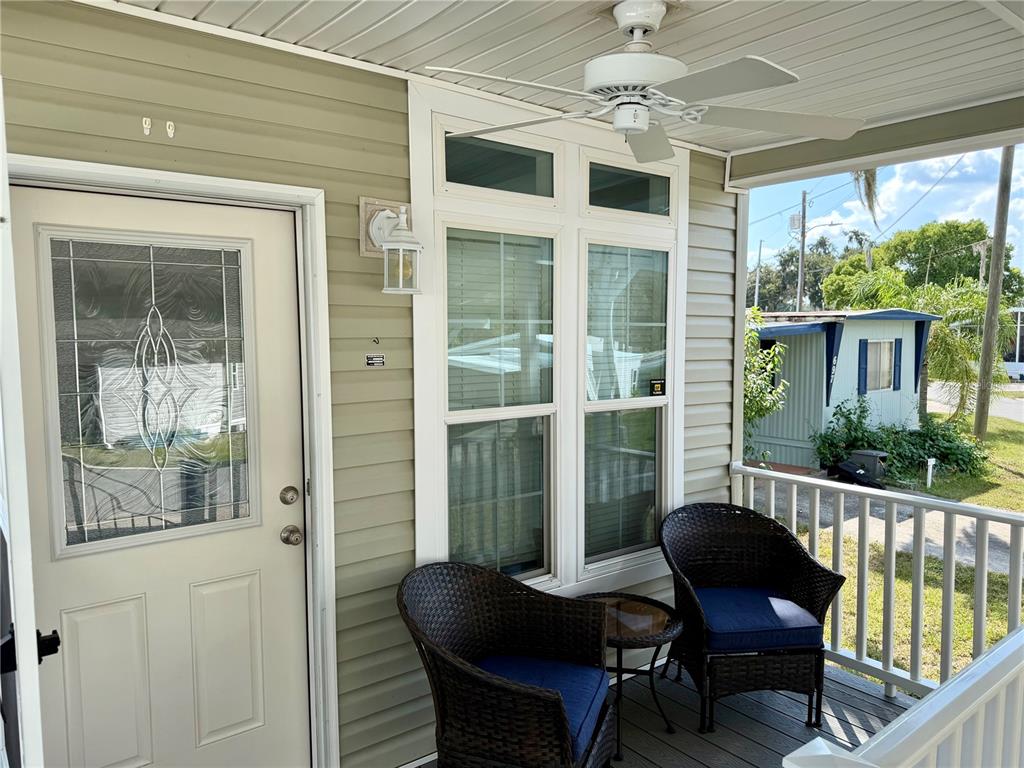 A covered front porch features light green siding, a ceiling fan, and two wicker chairs — 699 CINDI AVENUE, LEESBURG, FL