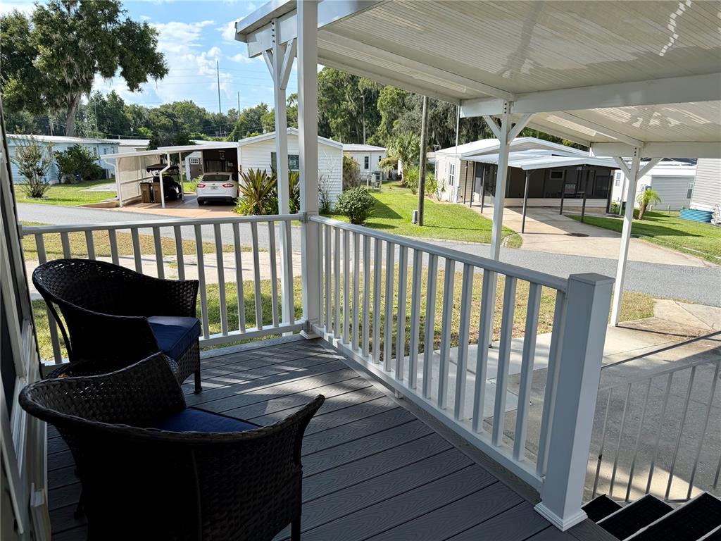 A covered porch with wicker chairs overlooks a residential street with mobile homes — 699 CINDI AVENUE, LEESBURG, FL