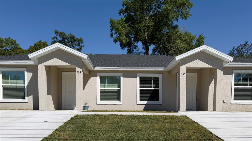 The exterior of a single-story duplex features beige stucco walls and two recessed entryways — 934 S APOPKA AVENUE, INVERNESS, FL