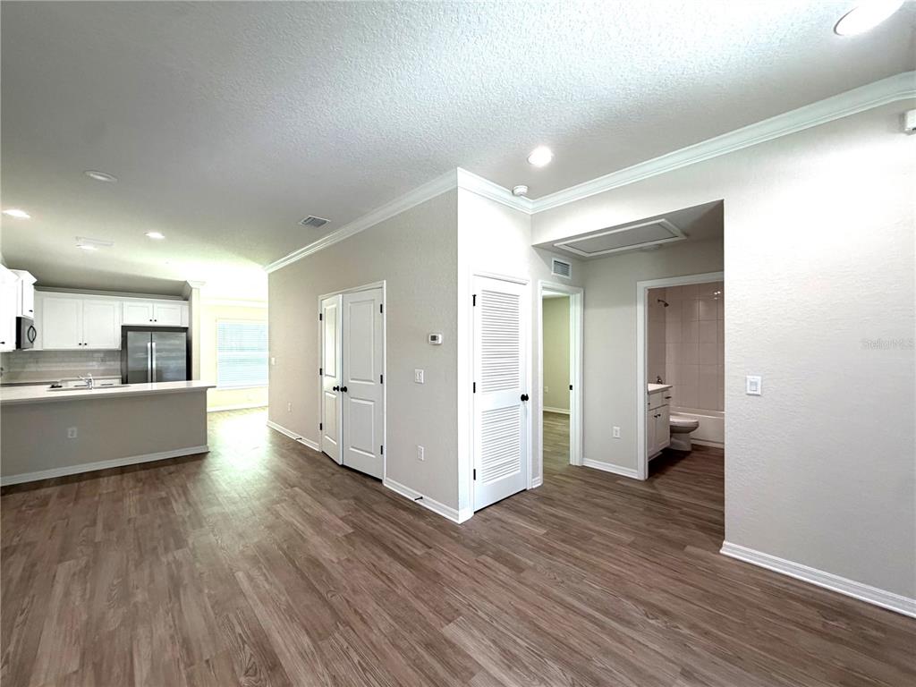 A view of a kitchen, hallway, and bathroom with light wood-look flooring and white doors — 934 S APOPKA AVENUE, INVERNESS, FL