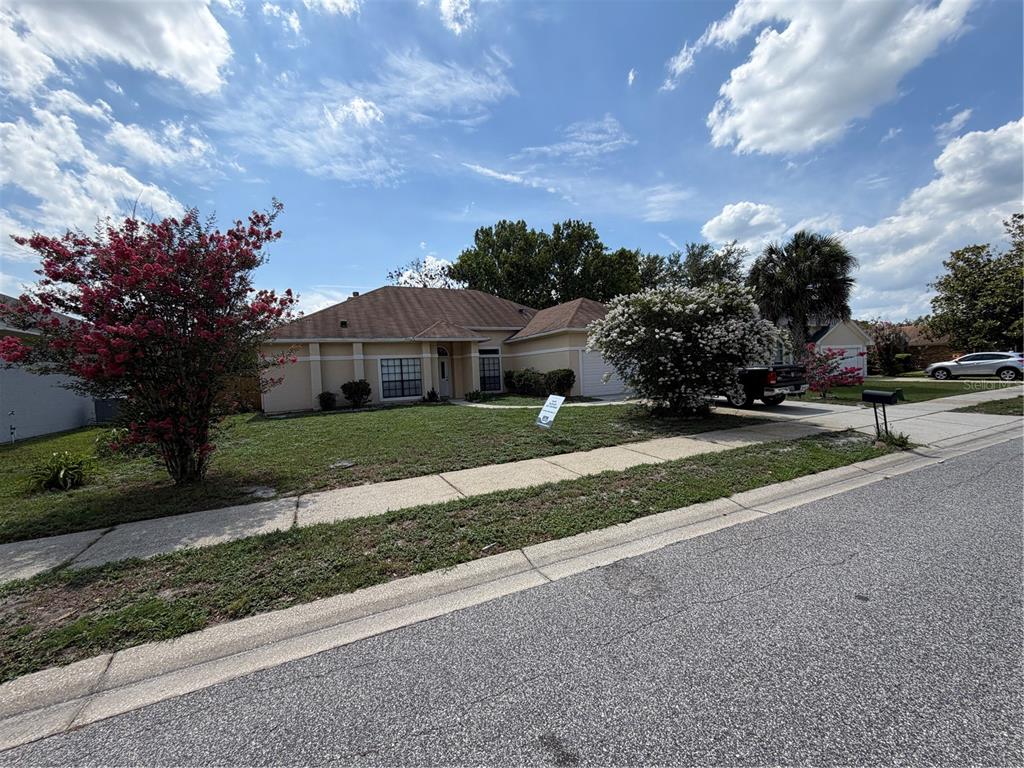 A single-story house with a tan exterior, a brown roof, and a front yard — 1009 CORKWOOD DRIVE, OVIEDO, FL