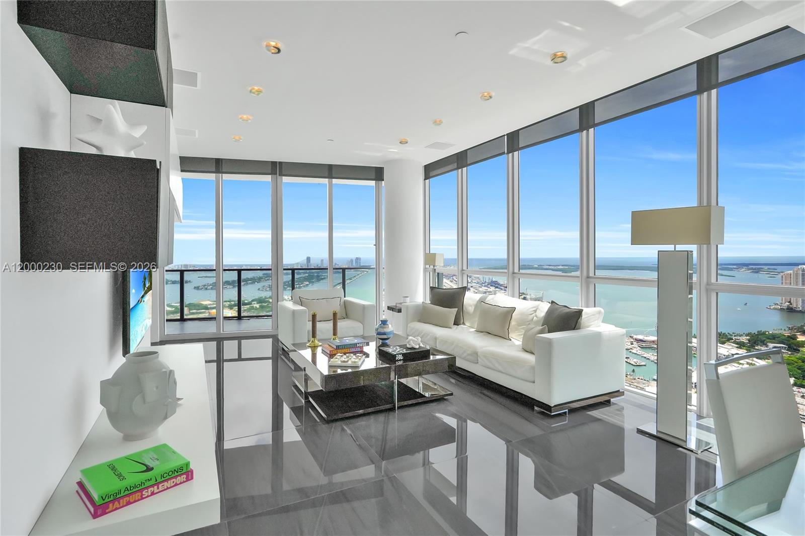 A modern living room with floor-to-ceiling windows, white furniture, and glossy dark tile flooring — 1100 Biscayne Blvd # 6001, Miami FL 33132, MIAMI, FL