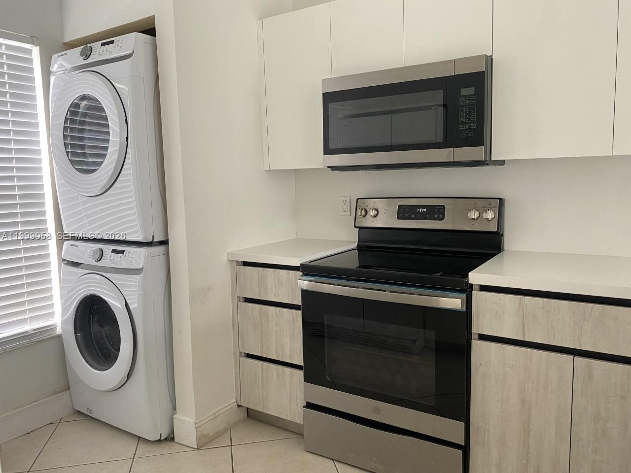 A kitchen features a stacked washer and dryer, stainless steel appliances, and light wood cabinetry — 219 SE 8th St # 601, Hallandale Beach FL 33009, HALLANDALE BEACH, FL