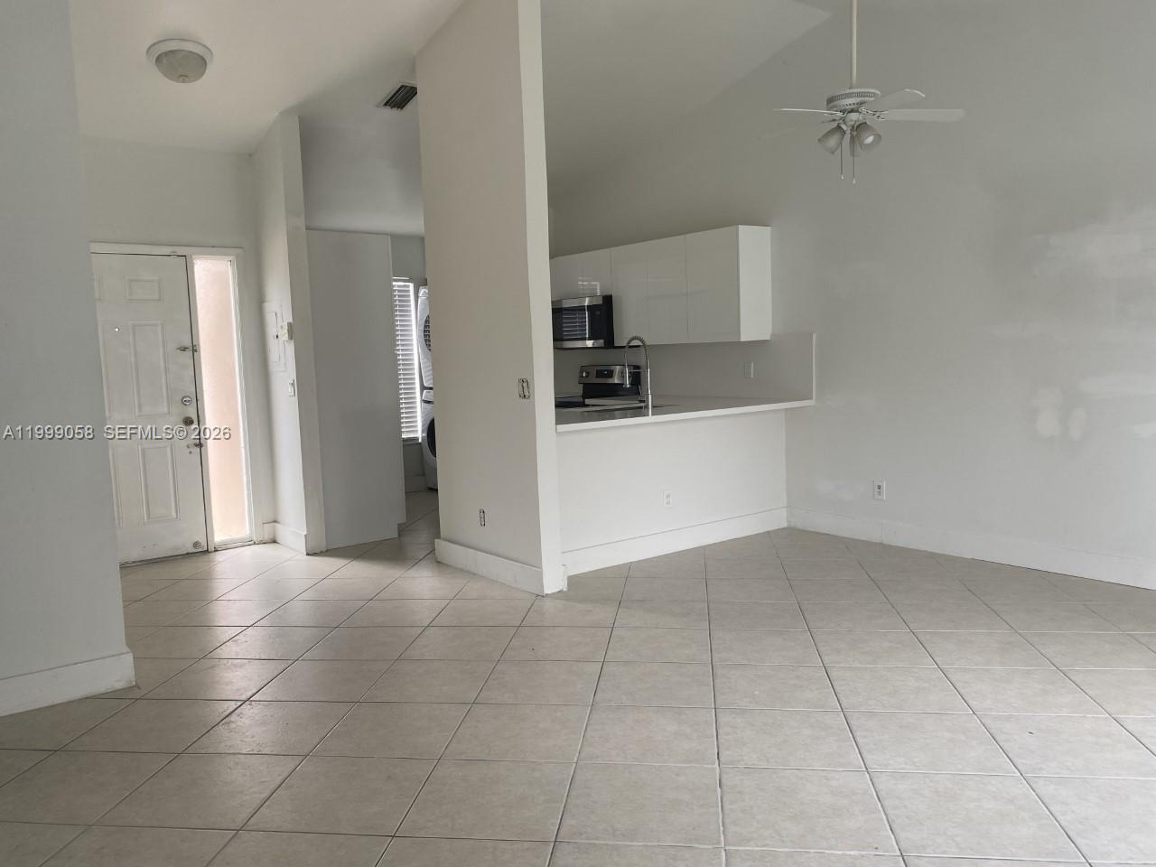 An open-concept living area features tile flooring, a white kitchen, and a ceiling fan — 219 SE 8th St # 601, Hallandale Beach FL 33009, HALLANDALE BEACH, FL