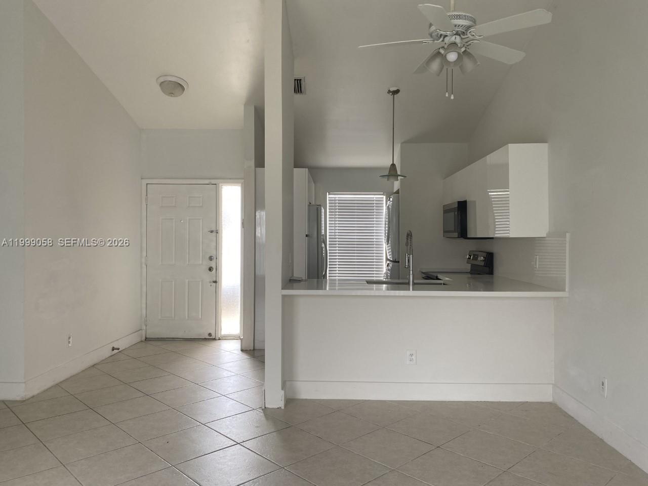A kitchen with white cabinets and a breakfast bar overlooks a tiled entryway — 219 SE 8th St # 601, Hallandale Beach FL 33009, HALLANDALE BEACH, FL