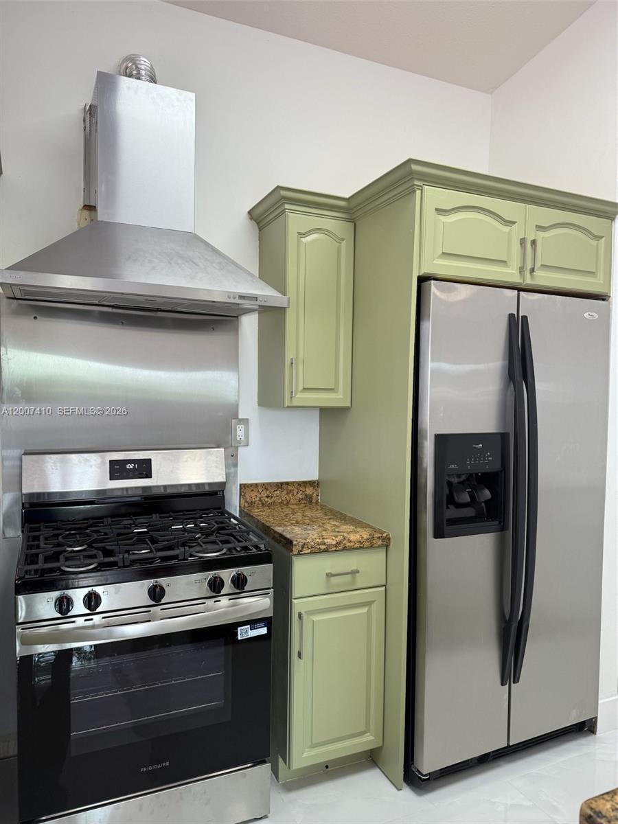 A kitchen features a stainless steel stove, range hood, refrigerator, and light green cabinetry — 10058 SW 156th Ct, Miami FL 33196, MIAMI, FL