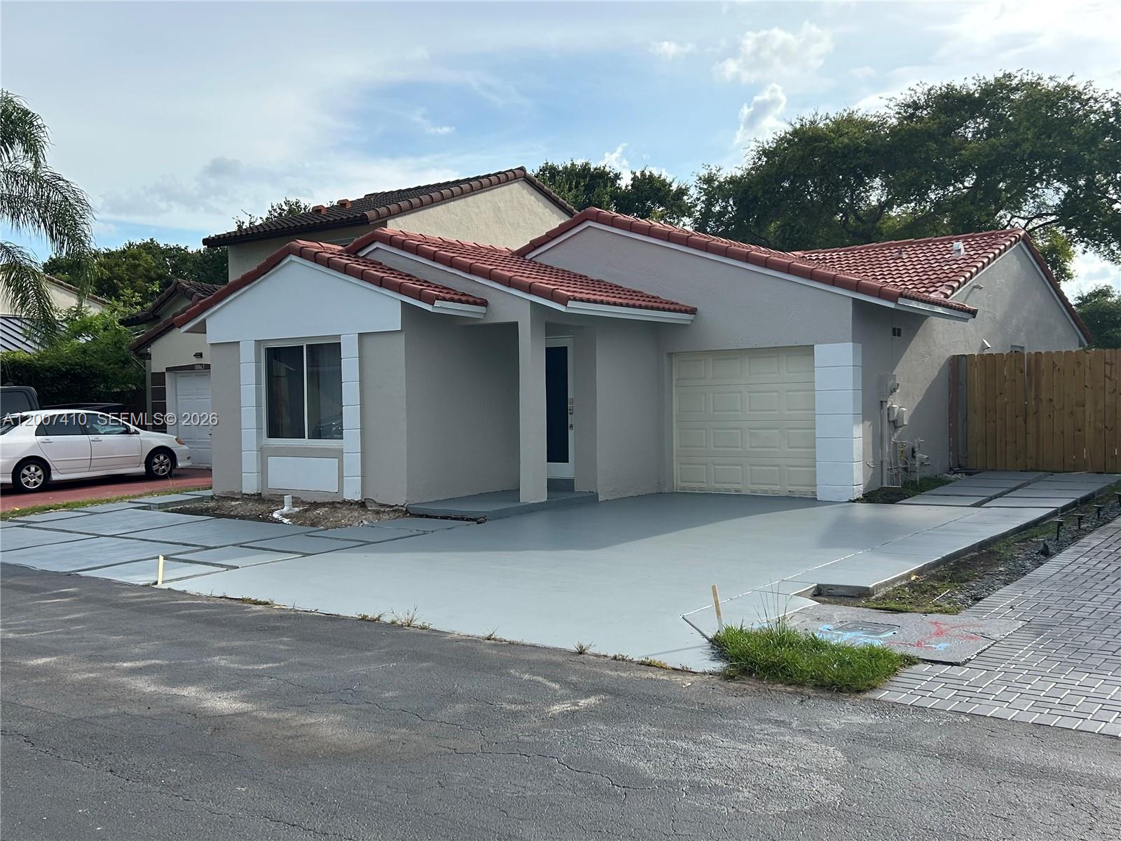 A single-story house with a red tile roof, gray exterior, and a paved driveway — 10058 SW 156th Ct, Miami FL 33196, MIAMI, FL