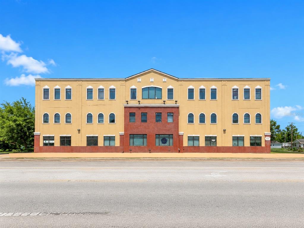 A three-story commercial building with a tan stucco facade and a central red brick section — 213 S DILLARD STREET UNIT 230, WINTER GARDEN, FL