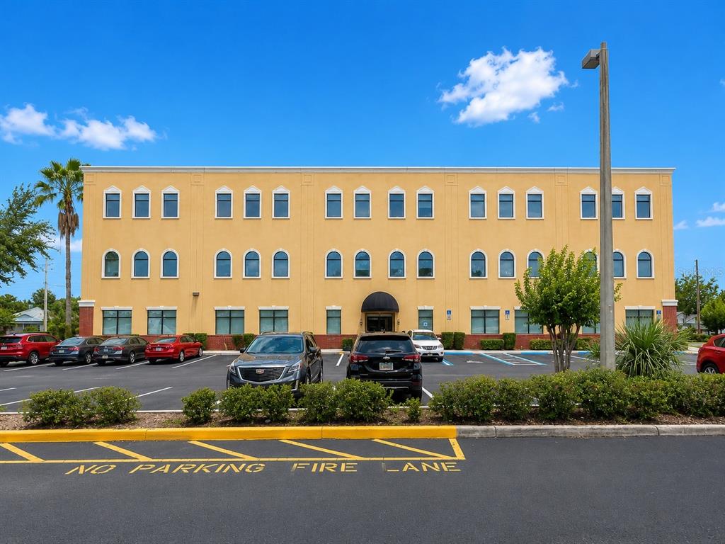 A three-story yellow commercial building with a parking lot in the foreground — 213 S DILLARD STREET UNIT 230, WINTER GARDEN, FL