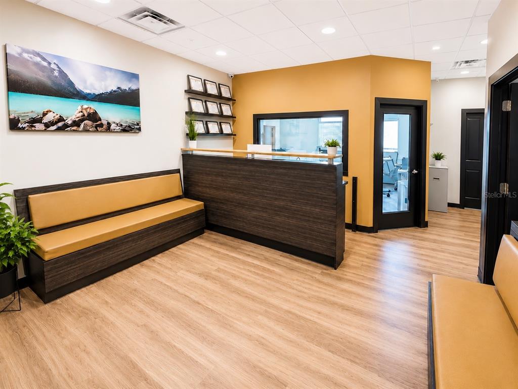 A waiting room features a wooden reception desk, built-in bench seating, and light wood flooring — 213 S DILLARD STREET UNIT 230, WINTER GARDEN, FL