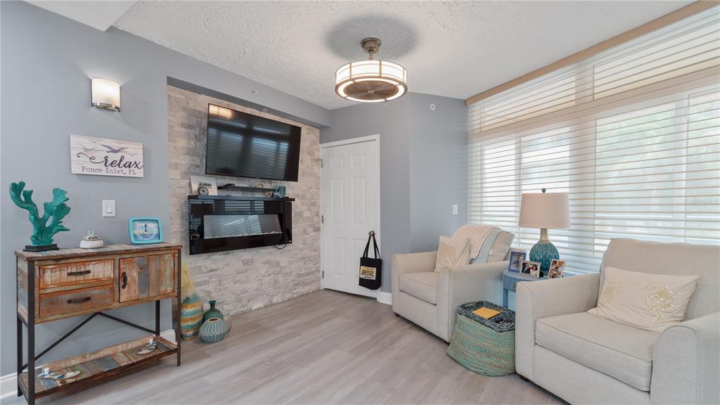 A living room features a stone accent wall with a fireplace, television, and two armchairs — 4565 S ATLANTIC AVENUE UNIT 5110, PORT ORANGE, FL