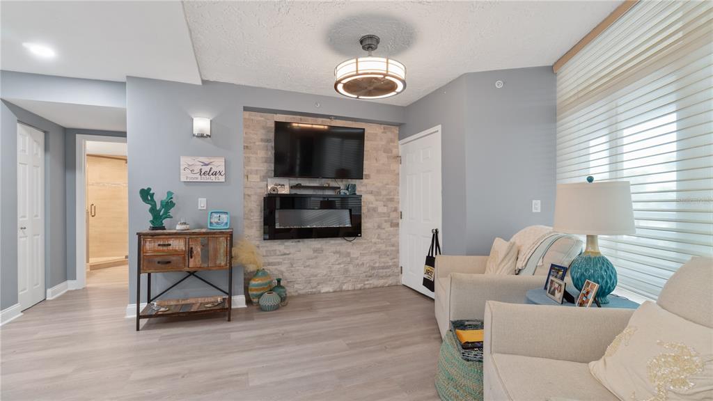 A living room features a stone accent wall with a mounted television and electric fireplace — 4565 S ATLANTIC AVENUE UNIT 5110, PORT ORANGE, FL