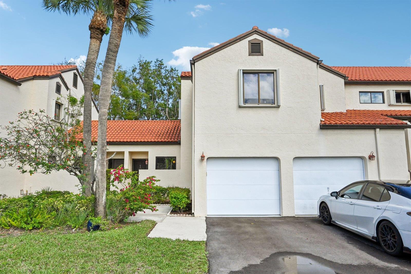 A two-story townhouse with a two-car garage, stucco exterior, and red tile roof — 22 Via De Casas # 103, Boynton Beach FL 33426, BOYNTON BEACH, FL