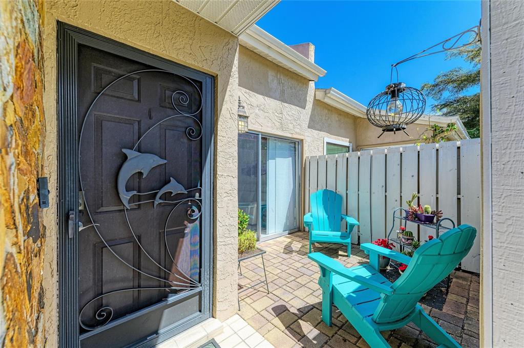A patio with two turquoise Adirondack chairs, a metal dolphin screen door, and a fence — 3405 TALLYWOOD LANE UNIT 7130, SARASOTA, FL