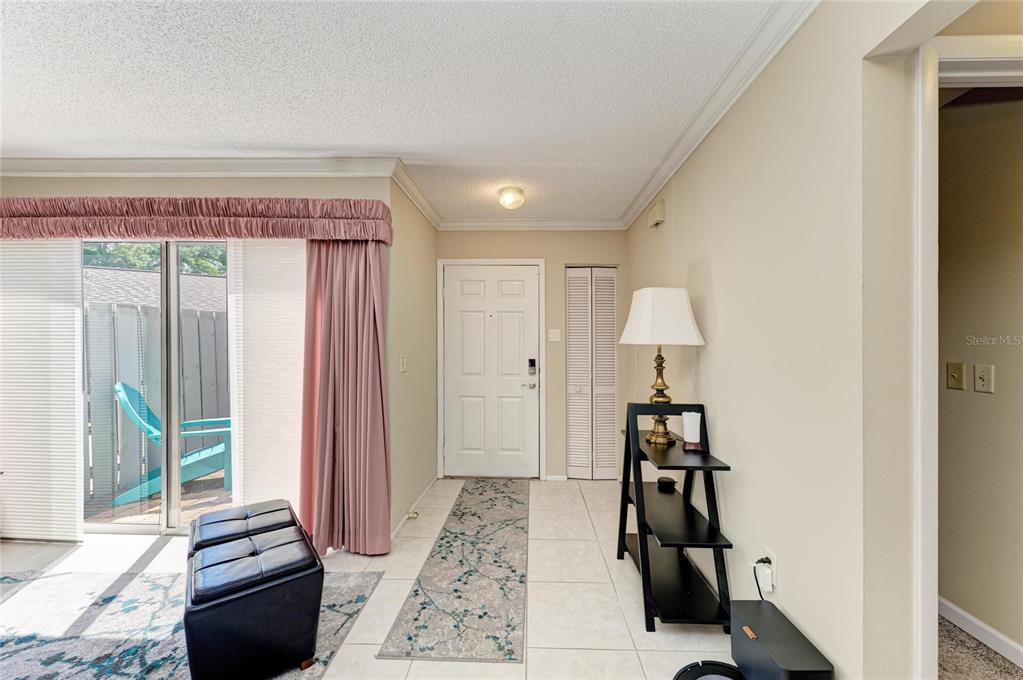 An entryway features tiled floors, a white front door, a closet, and a sliding glass door — 3405 TALLYWOOD LANE UNIT 7130, SARASOTA, FL